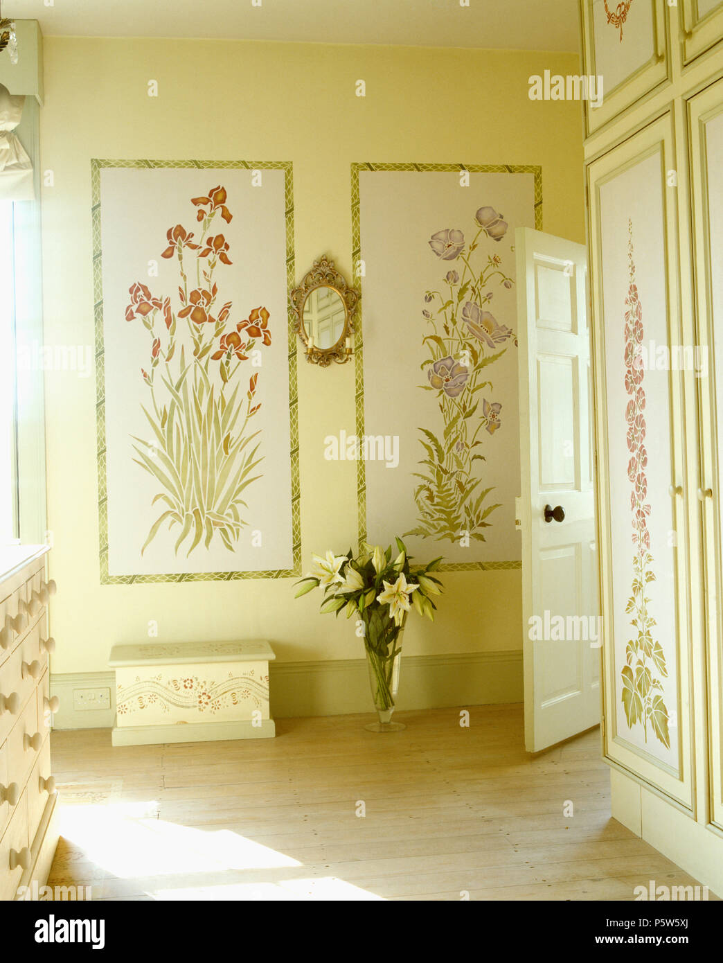 Stencilled flowering plants on walls of country bedroom with wooden flooring Stock Photo