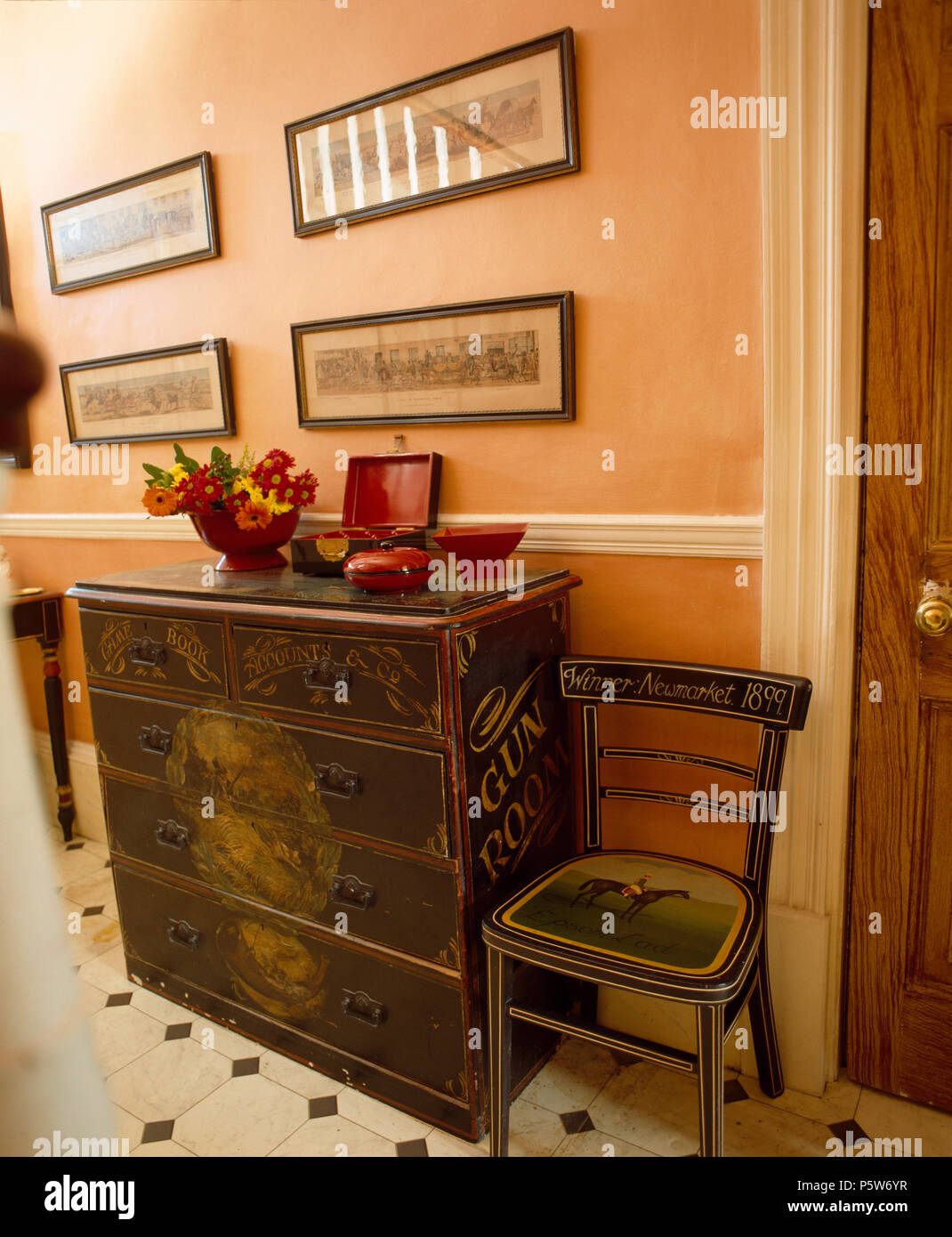Decoratively-painted vintage chest-of-drawers and chair in pale terracotta-painted hall Stock Photo