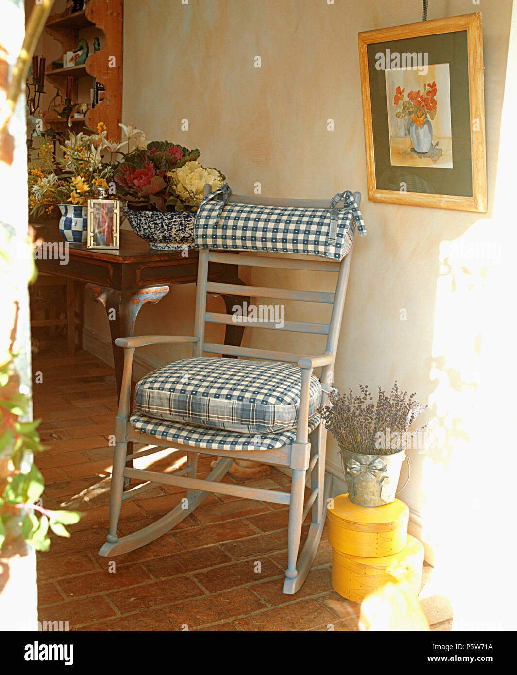 Lime-washed rocking chair with hand-made checked cushions in cottage hall Stock Photo