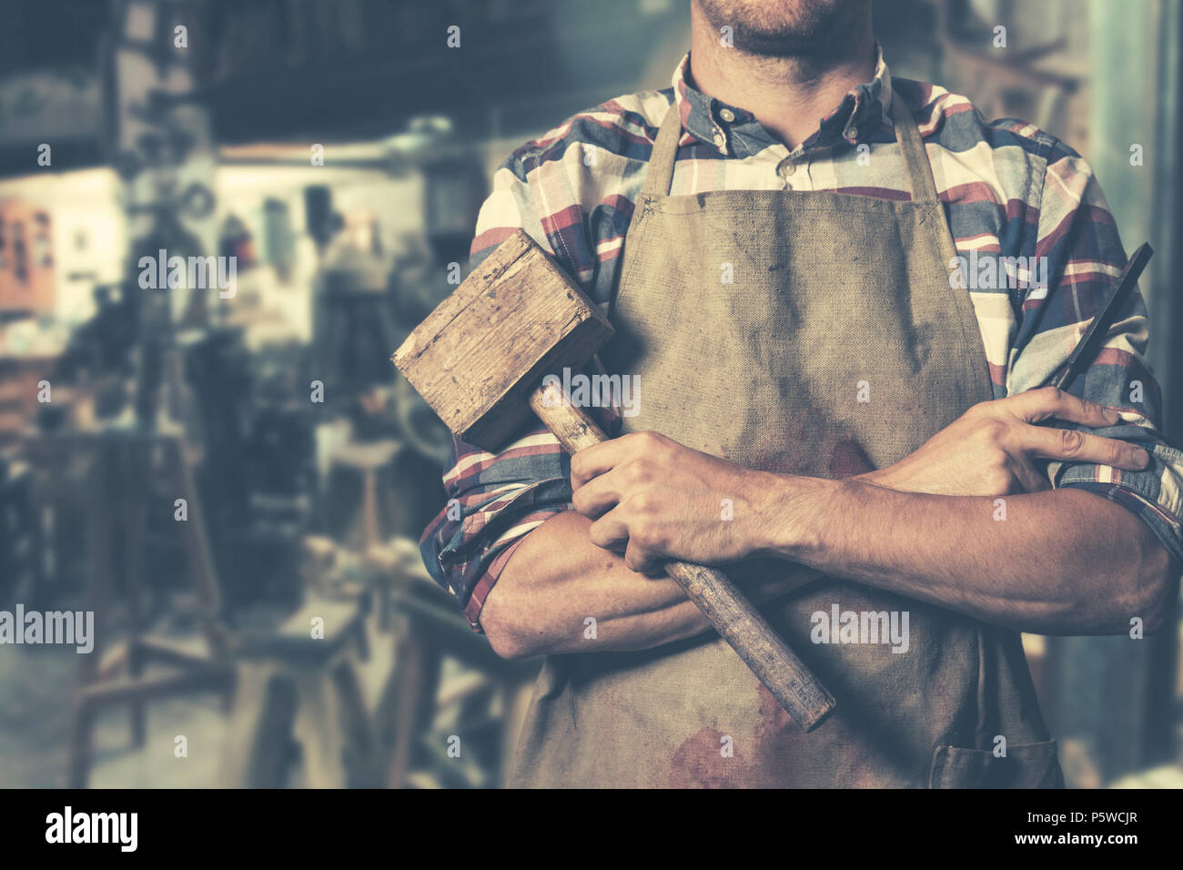 carpenter with hammer and chisel in hands in workshop Stock Photo