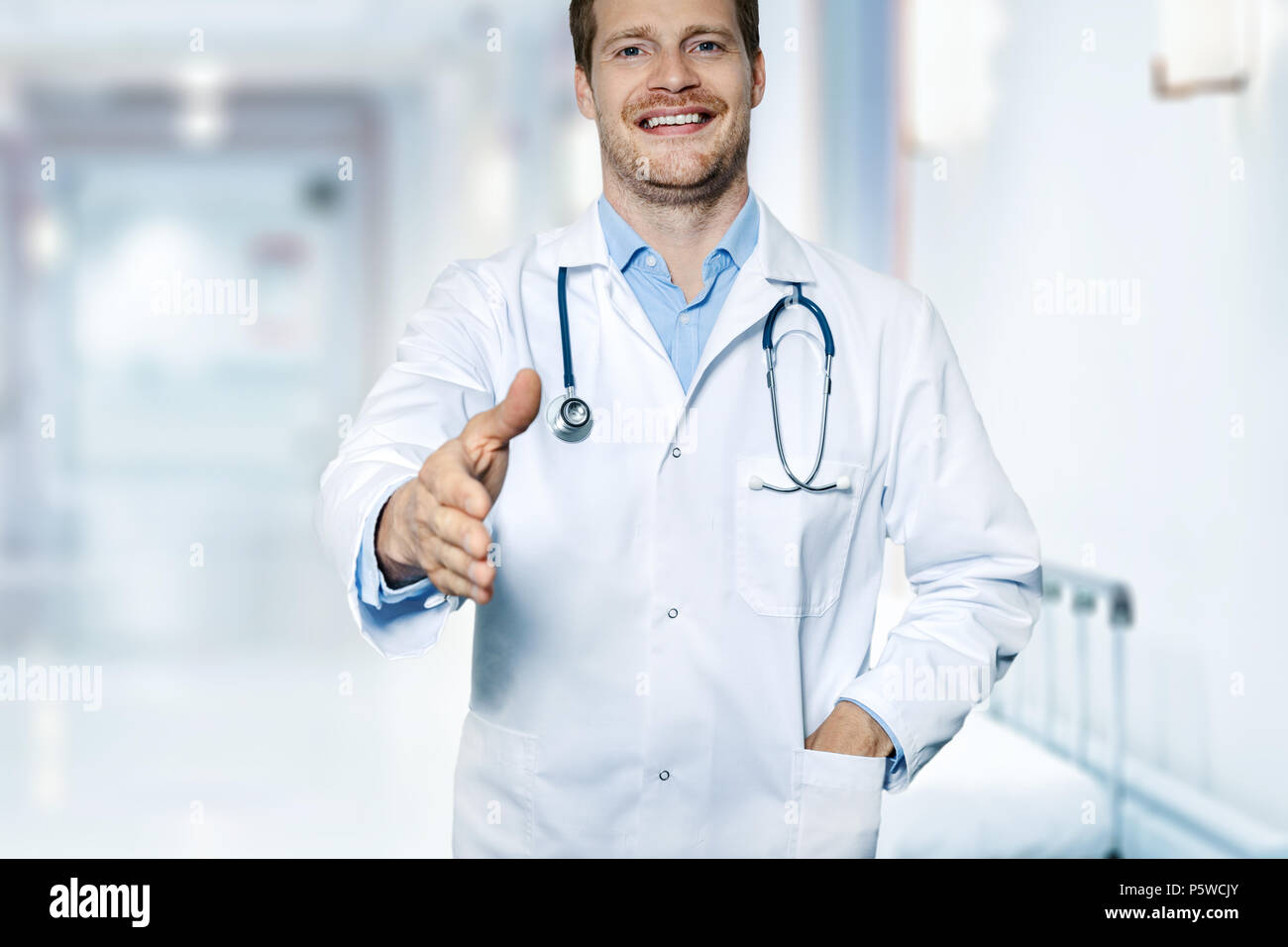 friendly smiling doctor standing in hospital hallway ready for handshake Stock Photo