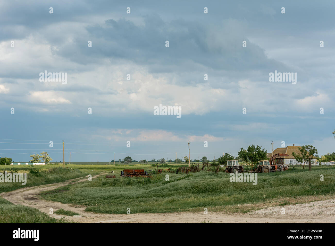 Agricultural equipment on a background of gloomy sky. Gloomy thunderous rural landscape. Stock Photo