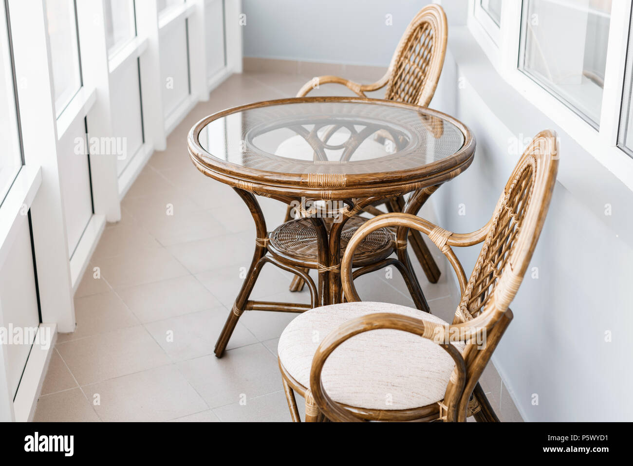 glass table and rattan wicker seat chair. Wicker furniture rattan table two  chairs near the window on balcony Stock Photo - Alamy