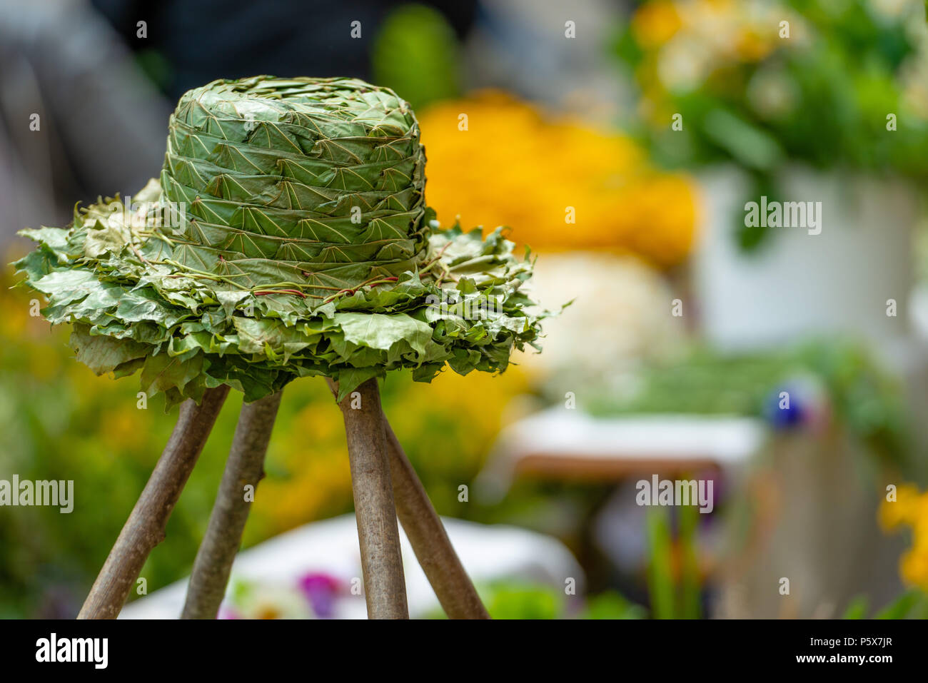 Wooden stand with a hat made of green wooden leaves. Stock Photo