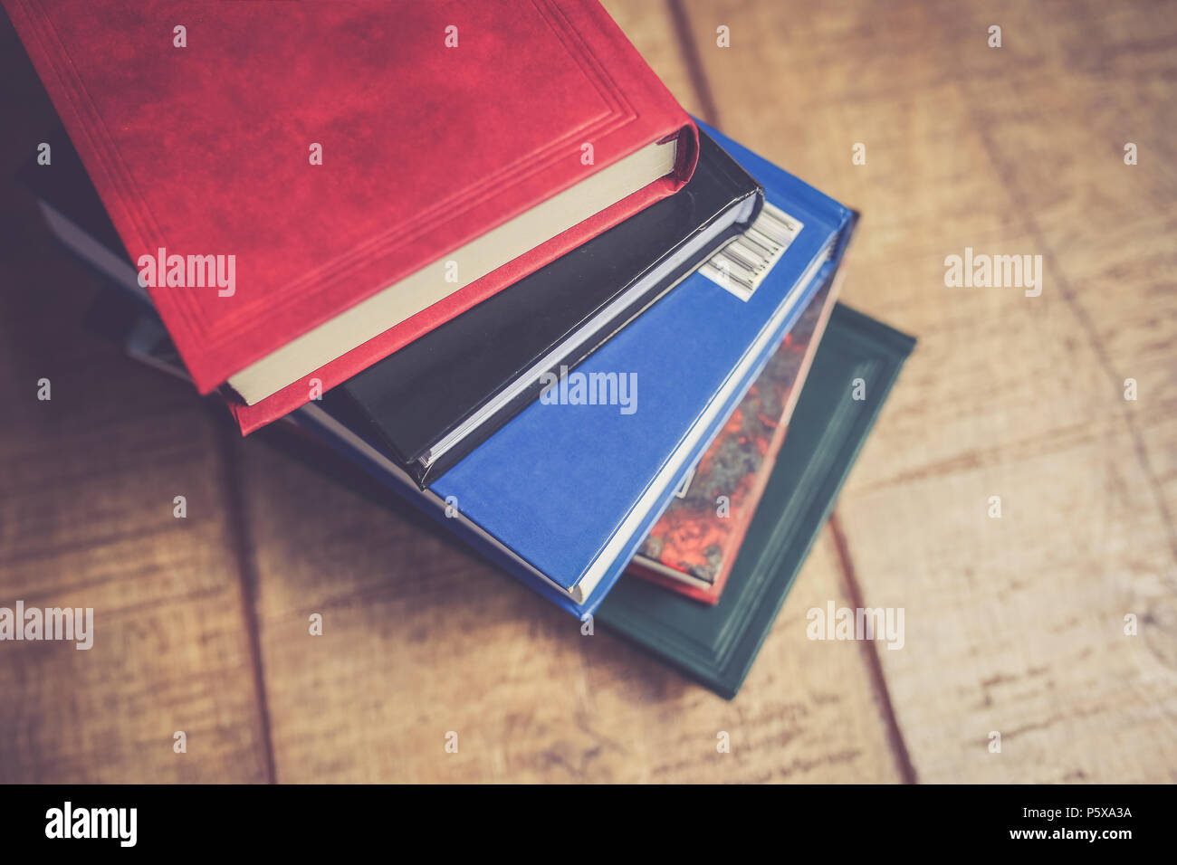 Pile of multiple color books on a wooden table Stock Photo
