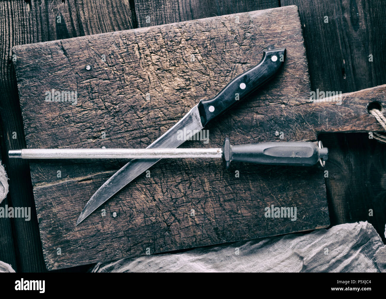 https://c8.alamy.com/comp/P5XJC4/old-knife-and-a-sharpener-on-a-brown-wooden-cutting-board-vintage-toning-P5XJC4.jpg