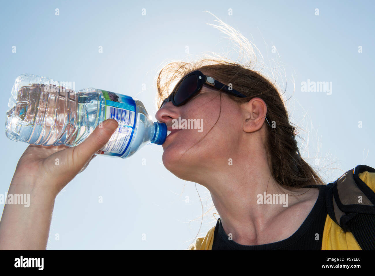 Model released woman enjoying a bottle of spring water on a hot day. Stock Photo