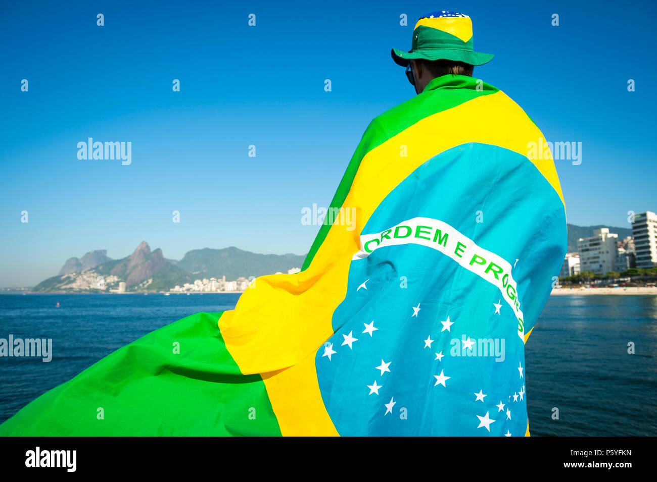 Brazilian Football Fan Wrapped In Giant Flag And Hat In Front Of Ipanema Beach City Skyline Rio De Janeiro Stock Photo Alamy