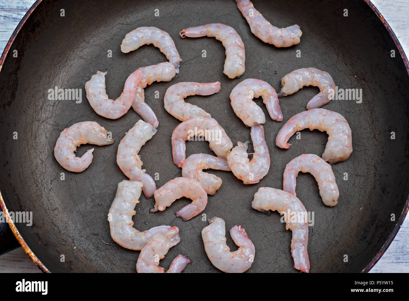 Fresh raw shrimp tails in old black cooking pot/ Food preparation/ Sea food background Stock Photo