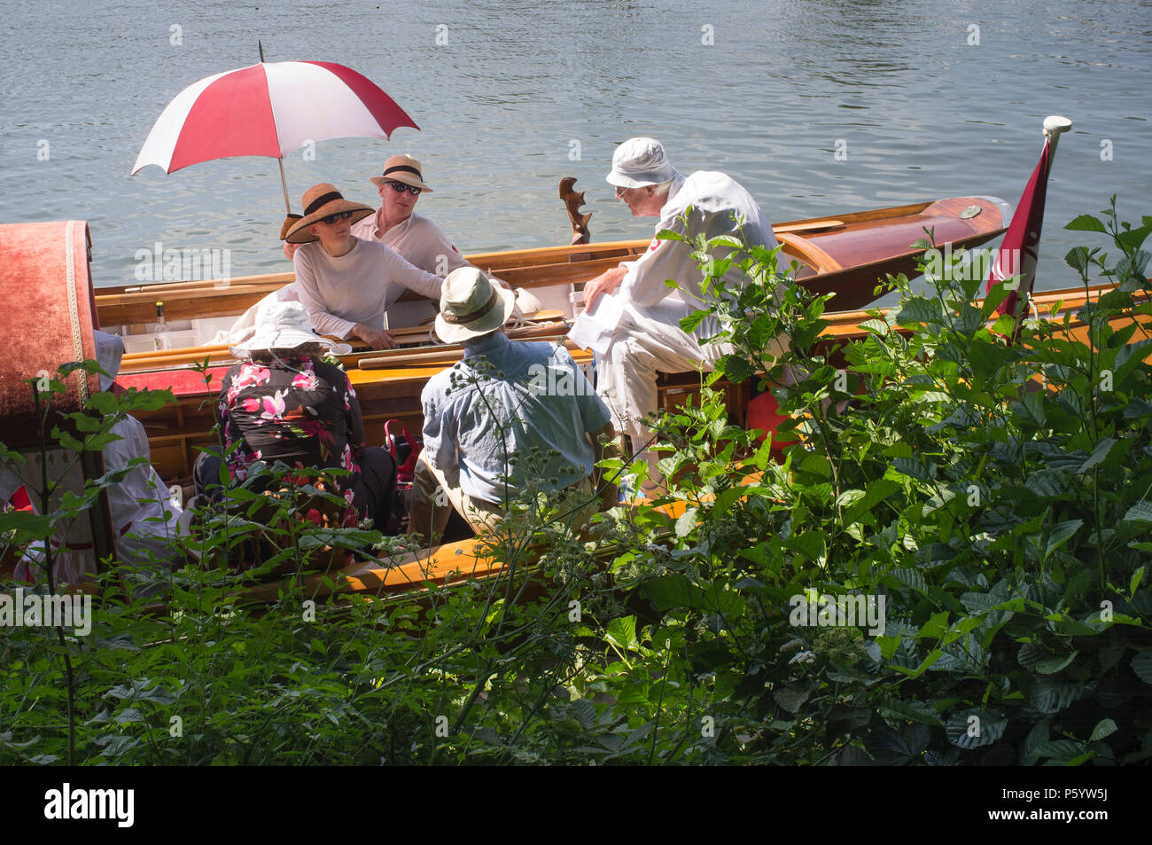 Party in their traditional vintage boats by the towpath at Henley Royal Regatta, Oxfordshire, UK Stock Photo