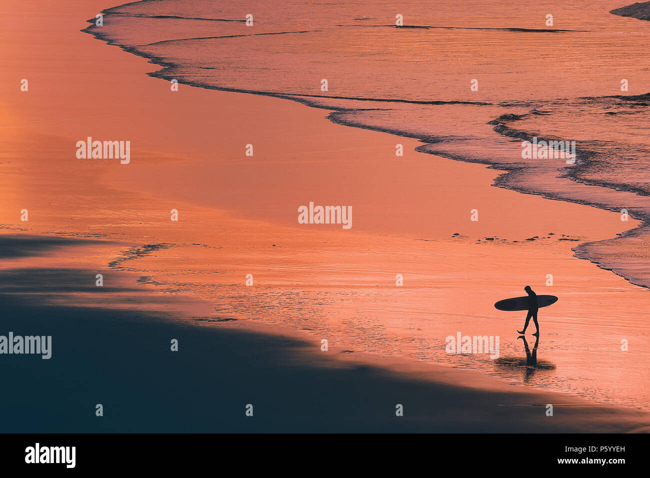 distant surfer silhouette in the shore at the sunset Stock Photo