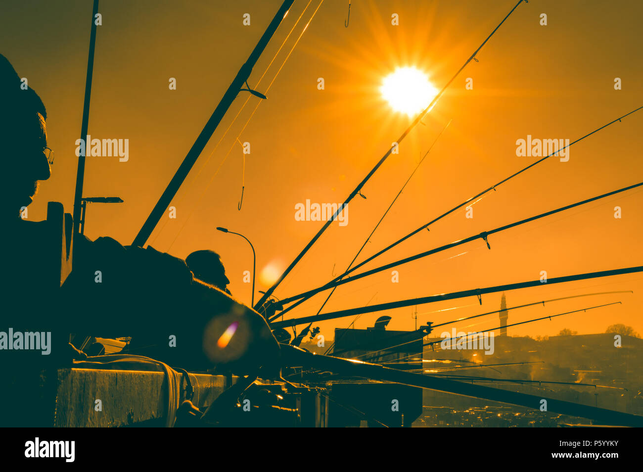 Silhouettes of fishermen fishing on Galata Bridge to relax and enjoy their hobby in Istanbul, Turkey Stock Photo