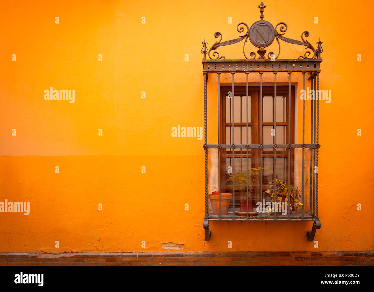 Antique medieval window with rusty iron bars and Russet orange orange wall in old Santa cruz quarter in Seville, Spain Stock Photo