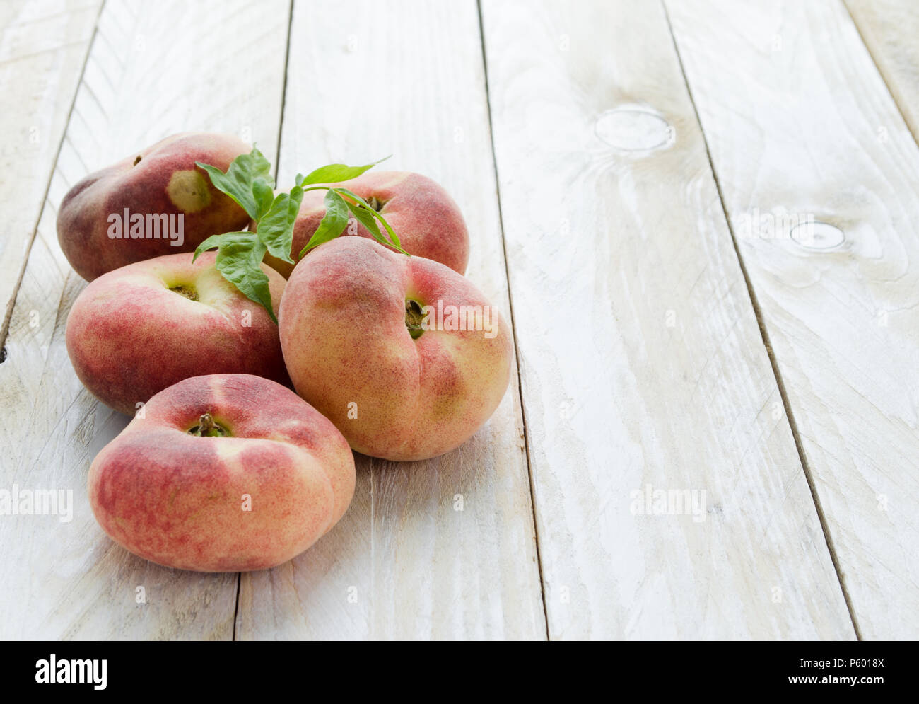Saturn peaches or UFO, donut, flat peaches on white wood boards Stock Photo