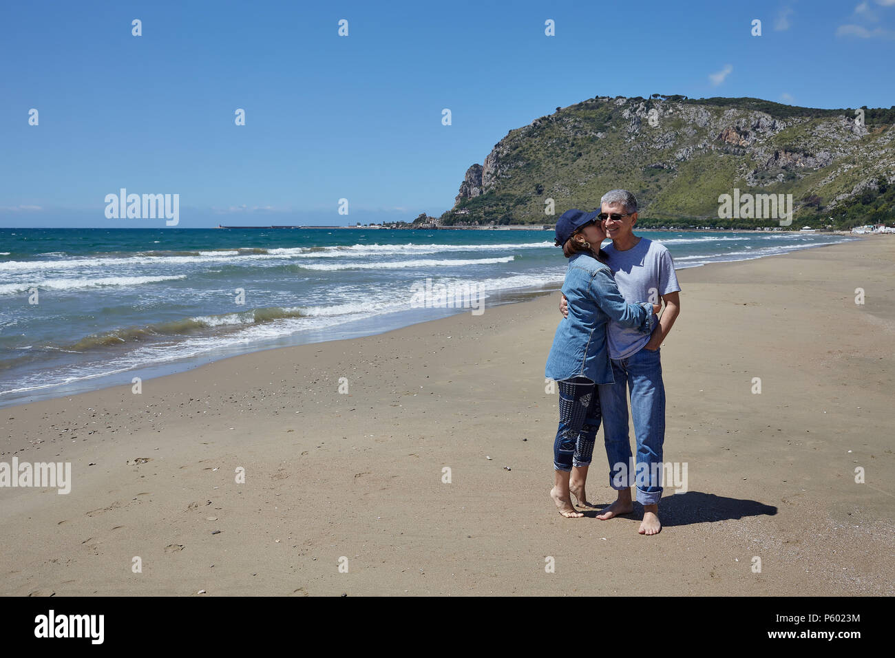 Happy Caucasian heterosexual couple barefoot on the beach. Stock Photo