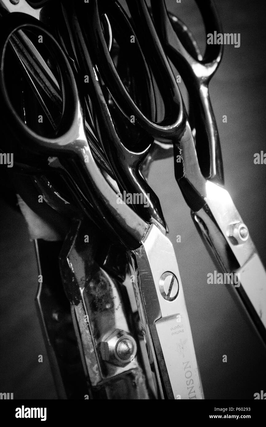 Collection of scissors in black and white hanging up in a workshop Stock Photo