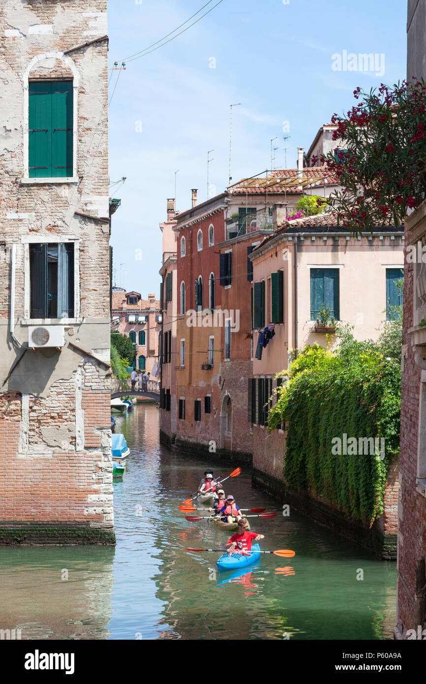 Kayakers in a canal in Cannaregio, Venice, Veneto, Italy, in rental kayaks, canoes with guide in evening light.  Vacatiom, holiday activity Stock Photo