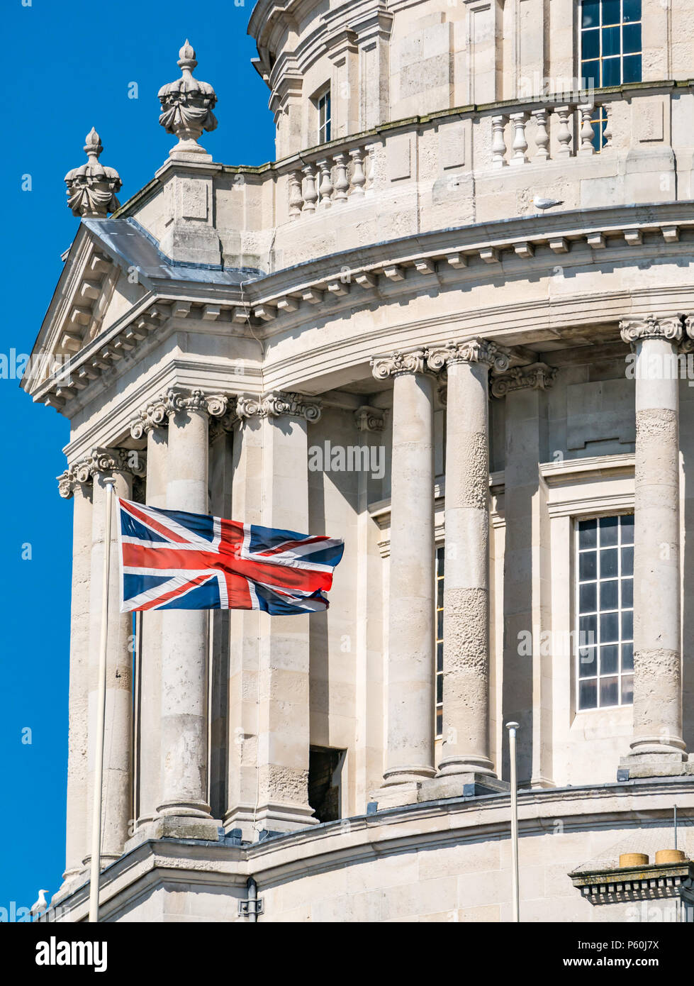 View of dome of Edwardian Baroque style of Liverpool building with Union Jack flag flying and blue sky Stock Photo