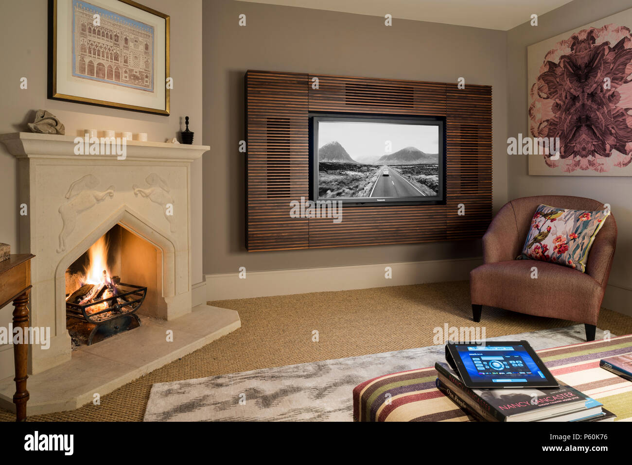 Lit fire by flat panel television in living room Stock Photo