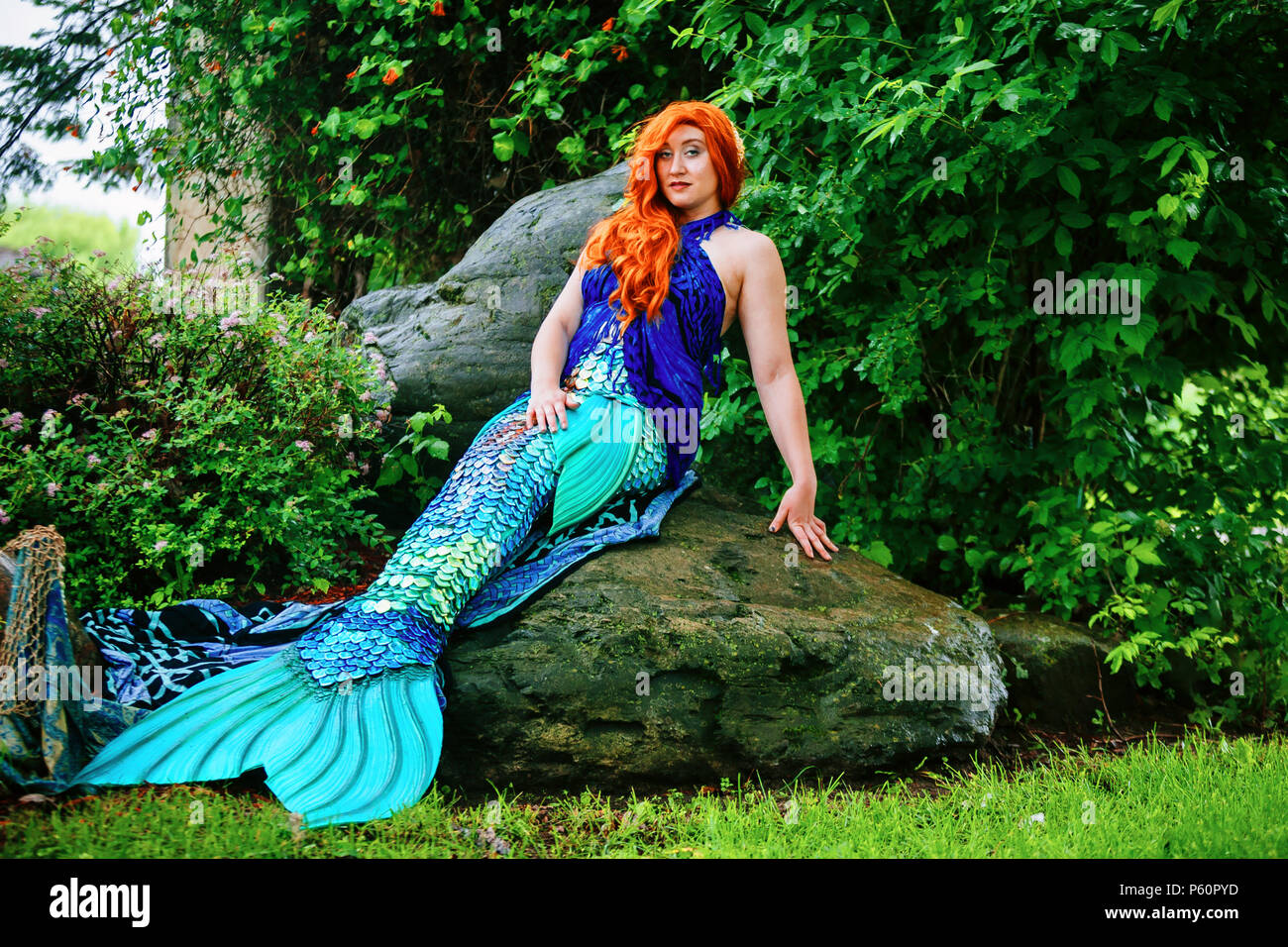 A Renaissance fair actor mermaid portrays her playful character while Stock Photo