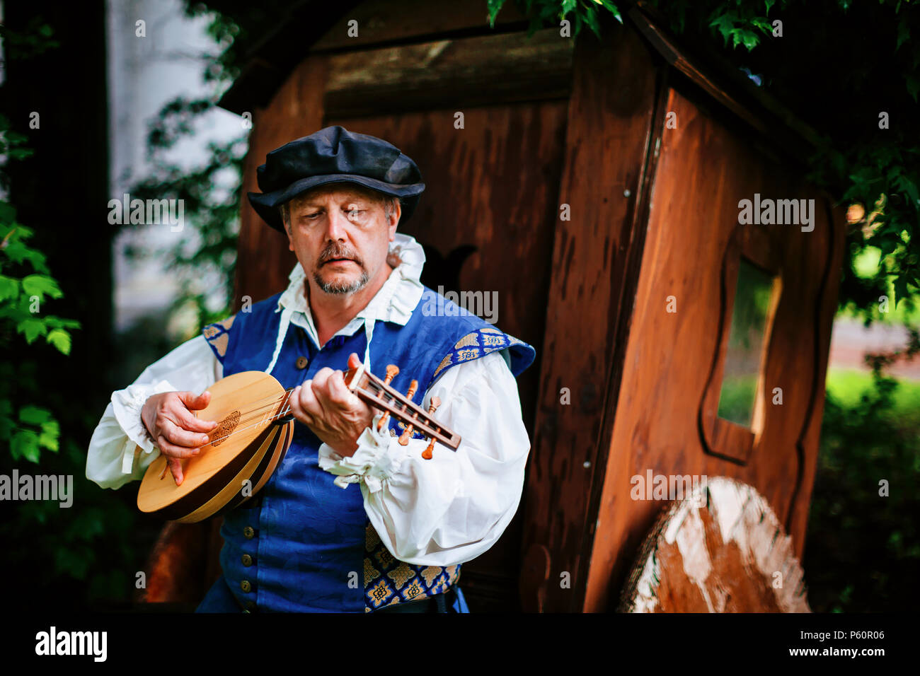A Renaissance fair actor dressed as a musician poses with his lute