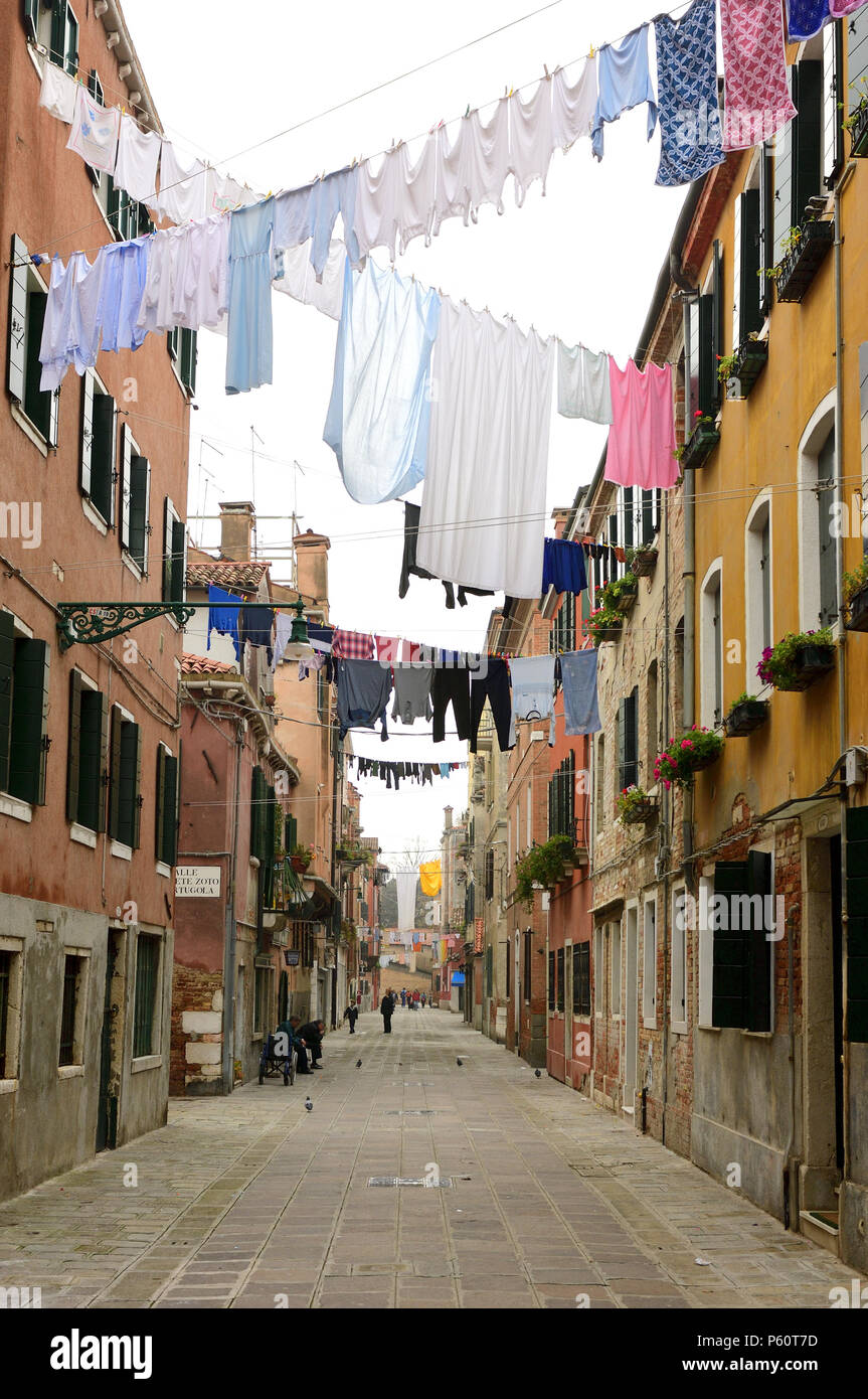 Washed laundry hangs between buildings in one of the off-beat residential neighborhoods of the Commune di Venezia and Centro Storico. Stock Photo