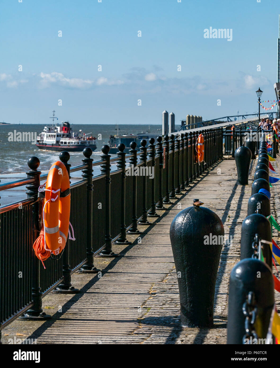Albert Dock riverside pedestrian walkway next to the River Mersey with Mersey ferry departing, Liverpool, England, UK Stock Photo