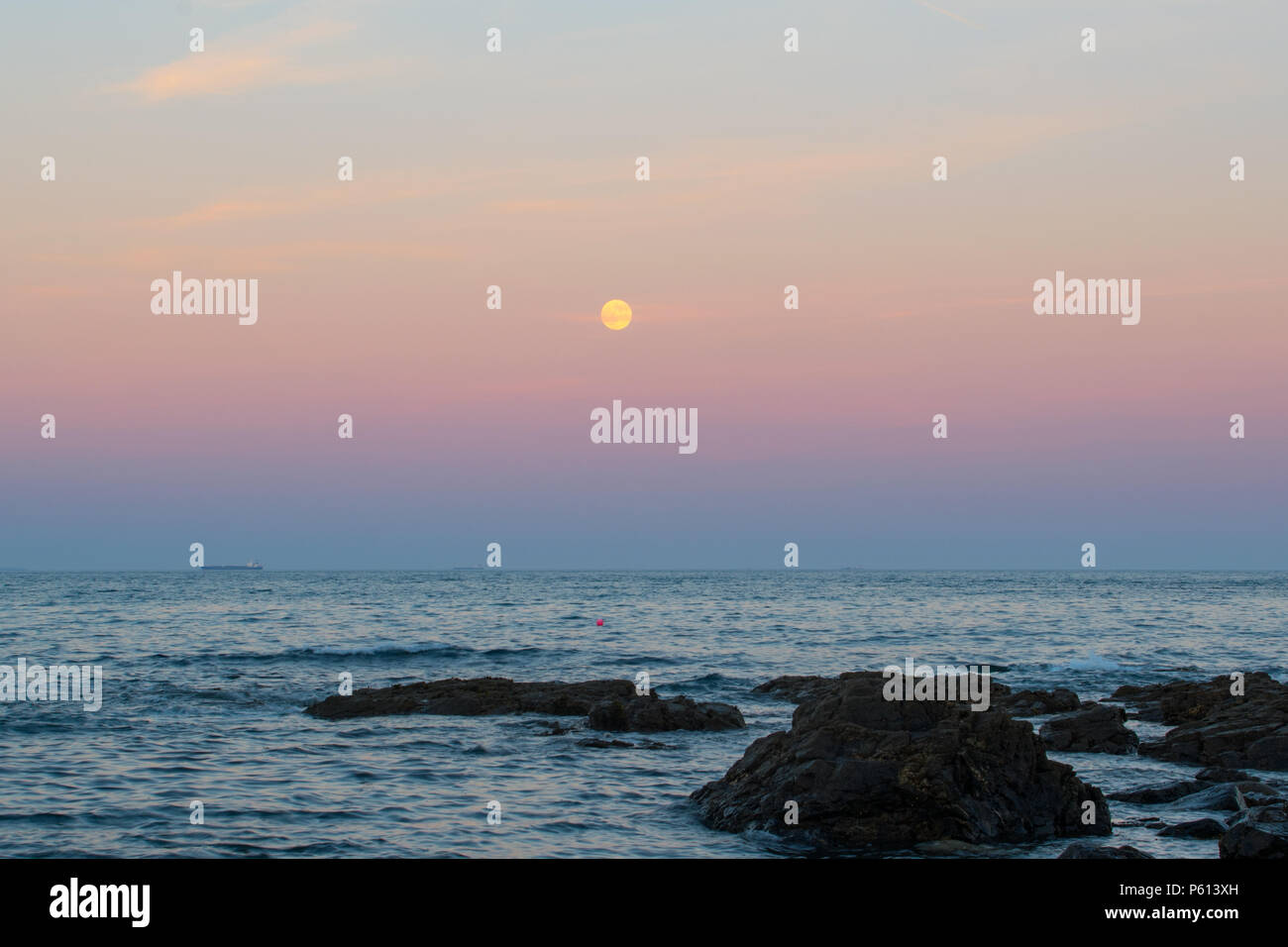 Mousehole, Cornwall, UK. 27th June 2018. Uk Weather.  The nearly full "Strawberry" Moon, rises over the sea at Mousehole at sunset this evening. Credit: cwallpix/Alamy Live News Stock Photo