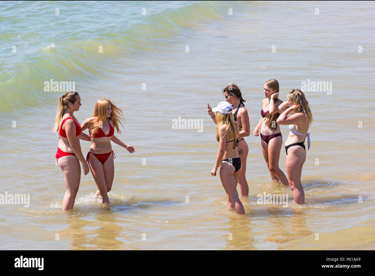 Bournemouth, Dorset, UK. 28th June, 2018. UK weather: sunseekers head to the beaches at Bournemouth on another hot sunny day with unbroken blue skies and sunshine. A slight breeze makes the heat more bearable. A group of friends in skimpy bikinis have fun playing in the sea and taking photos. Credit: Carolyn Jenkins/Alamy Live News Stock Photo