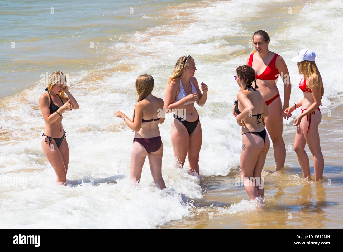Bournemouth, Dorset, UK. 28th June, 2018. UK weather: sunseekers head to the beaches at Bournemouth on another hot sunny day with unbroken blue skies and sunshine. A slight breeze makes the heat more bearable. A group of friends in skimpy bikinis have fun playing in the sea. Credit: Carolyn Jenkins/Alamy Live News Stock Photo