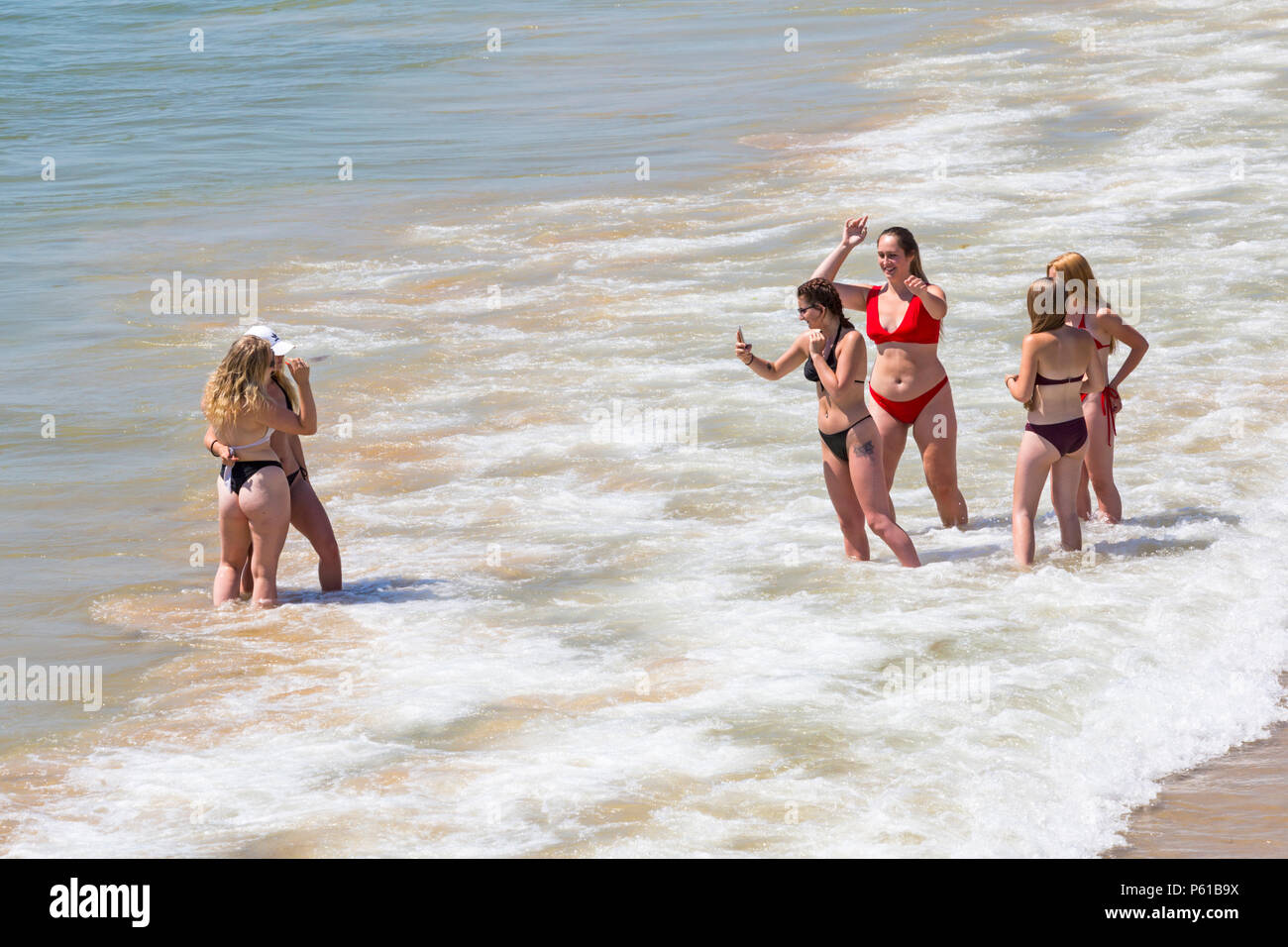 Bournemouth, Dorset, UK. 28th June 2018. UK weather: sunseekers head to the beaches at Bournemouth on another hot sunny day with unbroken blue skies and sunshine. A slight breeze makes the heat more bearable.  A group of friends in skimpy bikinis have fun playing in the sea and taking photos. Credit: Carolyn Jenkins/Alamy Live News Stock Photo