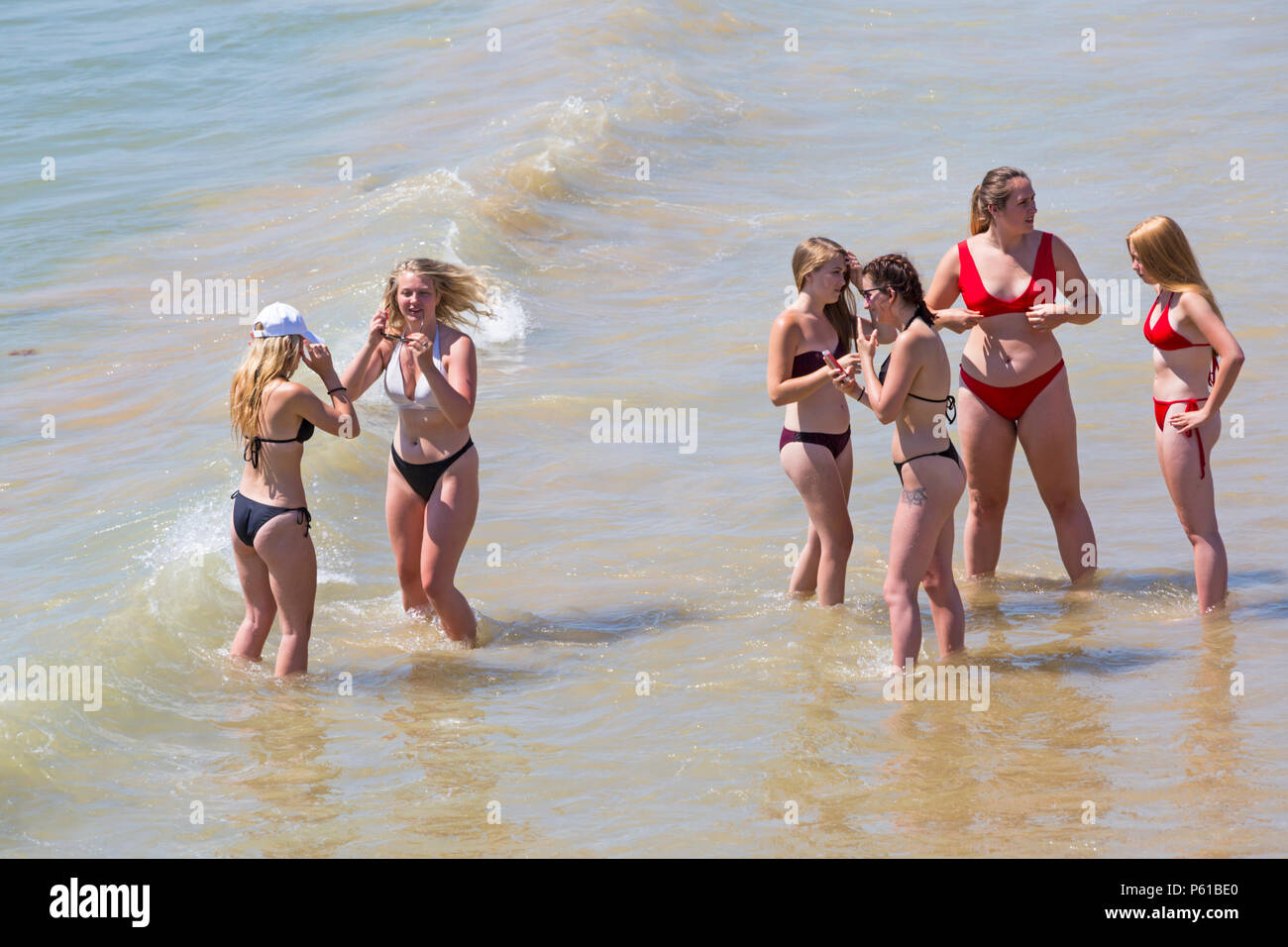 Bournemouth, Dorset, UK. 28th June 2018. UK weather: sunseekers head to the beaches at Bournemouth on another hot sunny day with unbroken blue skies and sunshine. A slight breeze makes the heat more bearable. A group of friends in skimpy bikinis have fun playing in the sea and taking photos. Credit: Carolyn Jenkins/Alamy Live News Stock Photo