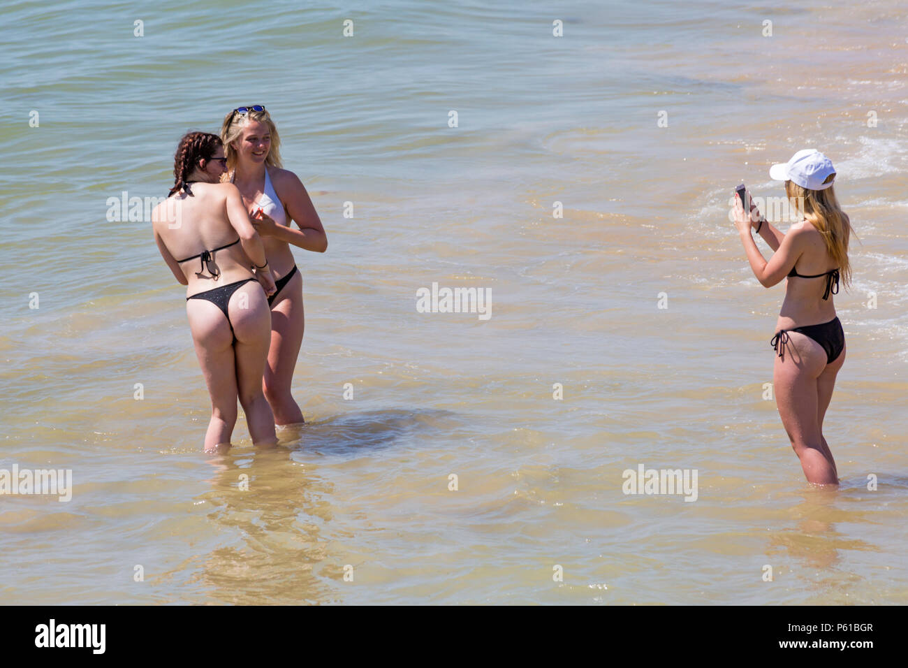 Bournemouth, Dorset, UK. 28th June 2018. UK weather: sunseekers head to the beaches at Bournemouth on another hot sunny day with unbroken blue skies and sunshine. A slight breeze makes the heat more bearable. A group of friends in skimpy bikinis have fun playing in the sea and taking photos. Credit: Carolyn Jenkins/Alamy Live News Stock Photo