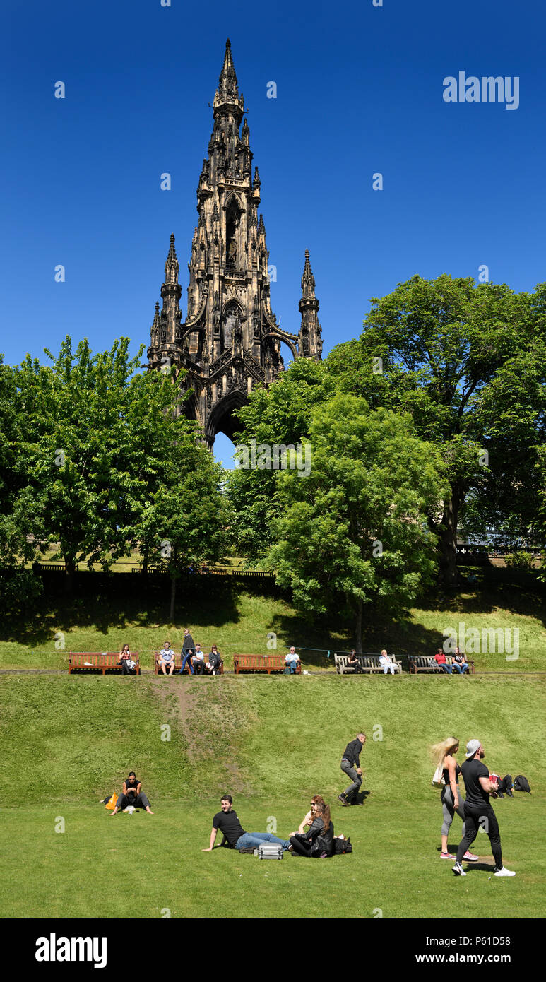 People and tourists in Princes Street Gardens park under the Scott Monument in Edinburgh Scotland UK with blue sky Stock Photo