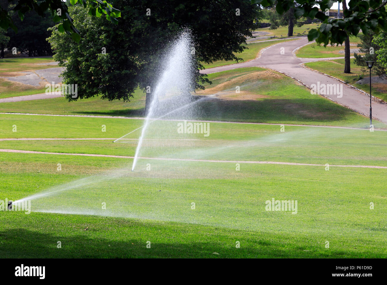 Sprinklers in park water the grass on a hot day of summer in Finland. Stock Photo