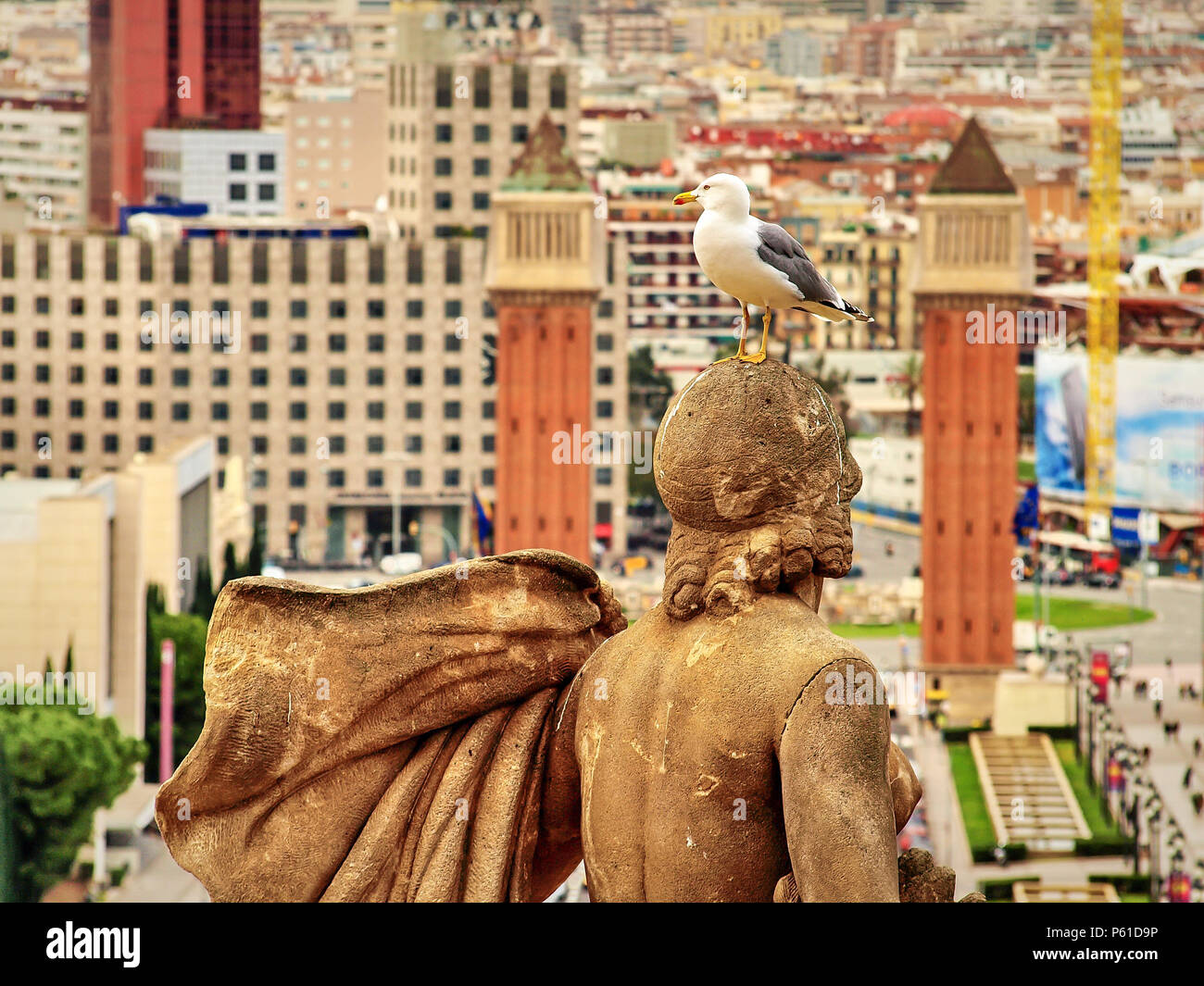An albatross on one of the statues on Montjuic with the Venetian Towers in the background in Barcelona, Spain Stock Photo