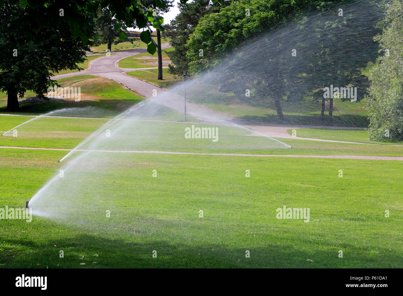 Sprinklers in park watering the grass on a hot day of summer in Finland. Stock Photo