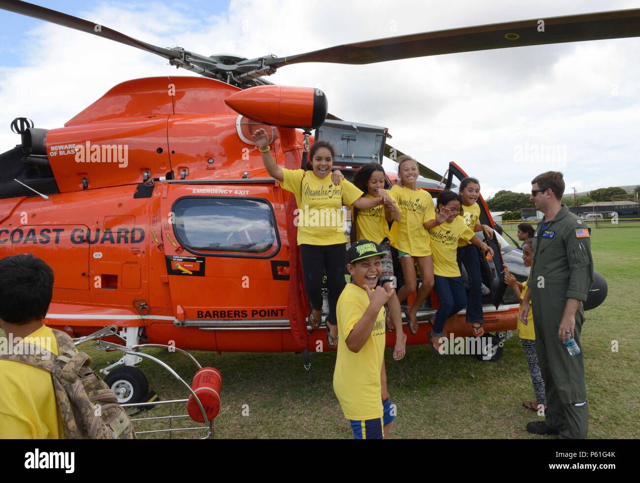 Lt. Jason Gross and several 5th graders from Moanalua Elementary School are all smiles in front of a Coast Guard MH-65 Dolphin helicopter during a D.A.R.E. rally at Kaunakakai Ball Park, Molokai, April 8, 2016. The rally was held to educate the children on the dangers of drugs and also included several static displays and from Coast Guard Air Station Barbers Point and several other first responder agencies. (U.S. Coast Guard photo by Petty Officer 2nd Class Tara Molle/Released) Stock Photo
