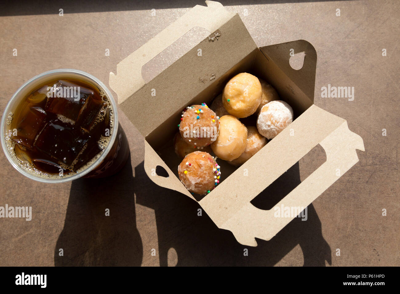 A box of Timbits served with iced coffee at a Tim Hortons store in Canada. Timbits are, essentially, flavoured doughnut pieces. Stock Photo