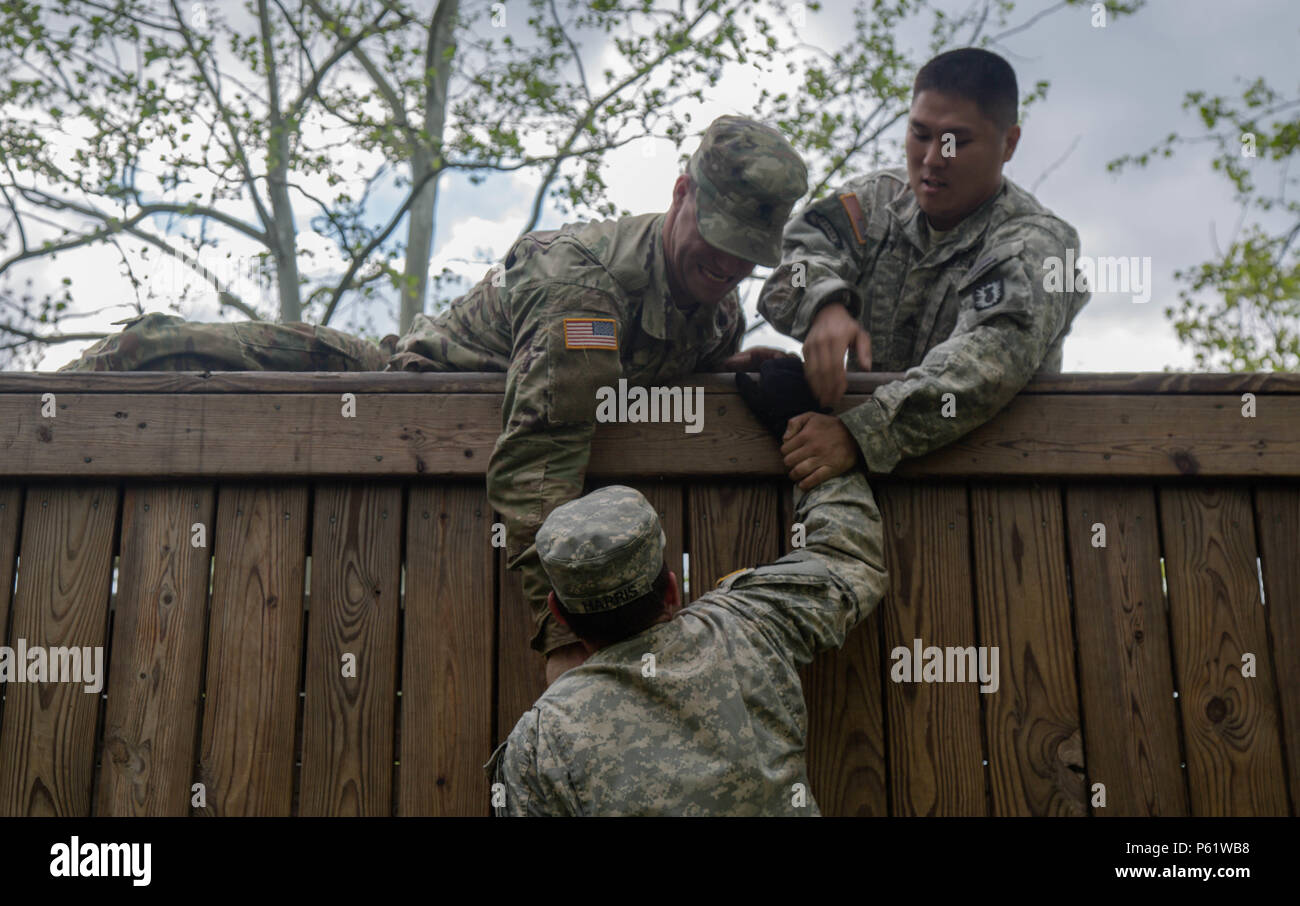 U.S. Army Soldiers, Spc. Jason Green (left), and Sgt. James Ahn, help pull up Staff Sgt. Jesse Harris, assigned to the 49th Ordnance Company (EOD), 184th Ordnance Battalion (EOD), for the final obstacle of the Field Leadership Reaction Course during 52D Ordnance Group (EOD) Team of the Year 2016 competition at the Wendell H. Ford Regional Training Center, Greenville, Ky., April 25, 2016. The weeklong competition tests teams, consisting of 3 EOD technicians, in various scenarios they may encounter in situations around the world, to determine the most physically, mentally, tactically, and techni Stock Photo