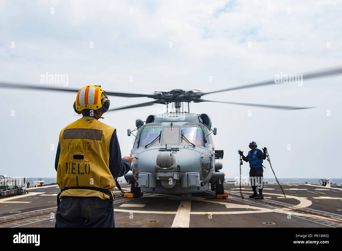 160406-N-MD297-051 PACIFIC OCEAN (April 6, 2016) - Boatswain's Mate 3rd Class Terry Davis, right, gestures that the chains securing an MH-60R helicopter from the 'Jaguars' of Helicopter Maritime Strike Squadron (HSM) 60 have been removed as the helicopter prepares to take off the flight deck aboard the Arleigh Burke-class guided-missile destroyer USS Lassen (DDG 82). Lassen is currently underway in support of Operation Martillo, a joint operation with the U.S. Coast Guard and partner nations within the 4th Fleet area of responsibility. Operation Martillo is being led by Joint Interagency Task  Stock Photo