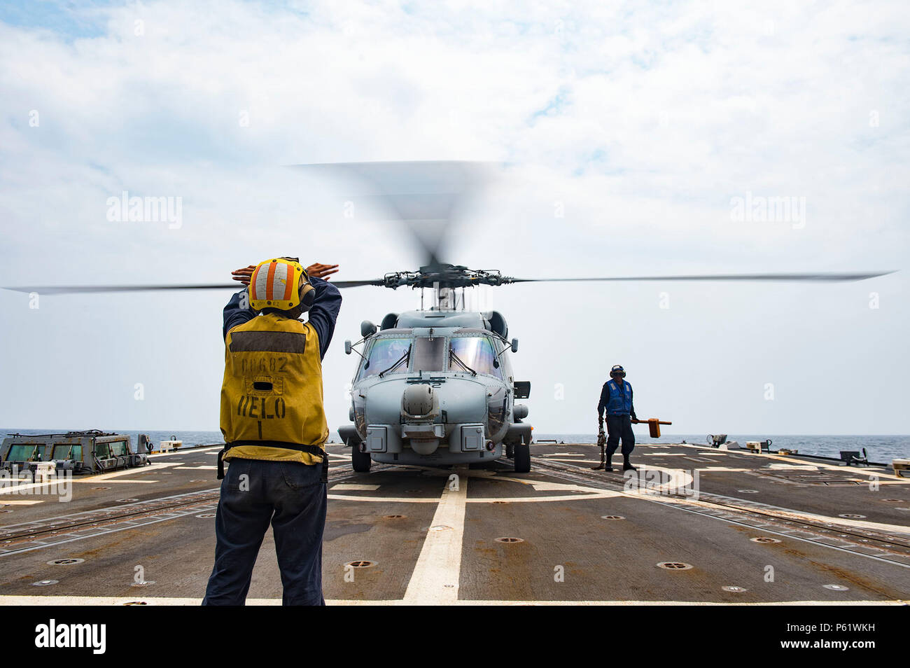 160406-N-MD297-053 PACIFIC OCEAN (April 6, 2016) - Logistics Specialist Seaman Sanndra Ton, assigned to the Arleigh Burke-class guided-missile destroyer USS Lassen (DDG 82), signals an MH-60R helicopter from the 'Jaguars' of Helicopter Maritime Strike Squadron (HSM) 60 that the chocks and chains have been removed from the helicopter. Lassen is currently underway in support of Operation Martillo, a joint operation with the U.S. Coast Guard and partner nations within the 4th Fleet area of responsibility. Operation Martillo is being led by Joint Interagency Task Force South, in support of U.S. So Stock Photo