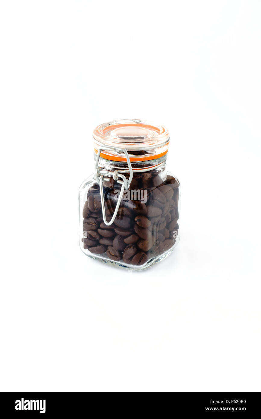 Mini preserving jar with wire clamp closure filled with roasted coffee beans on white background. Stock Photo