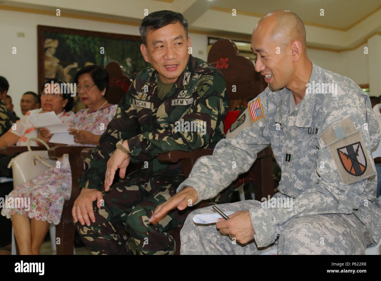Brig. Gen. Dinoh A. Dolina, Armed Forces of the Philippines (AFP) assistant division commander, 3rd Infantry Division (left), and U.S. Army Reserve Cpt. Kevin K. Tran, 303rd Maneuver Enhancement Brigade, operations officer in charge in support of Balikatan 2016 Combined Joint Civil Military Operations Task Force, exchange military knowledge at Camp Peralta, Capiz, Philippines, while waiting to view a video memoir of the historical Bataan Death March of 1942, April 09, 2016. The viewing followed a flag raising ceremony. The ceremony was one of many that have brought together the AFP and U.S. mi Stock Photo