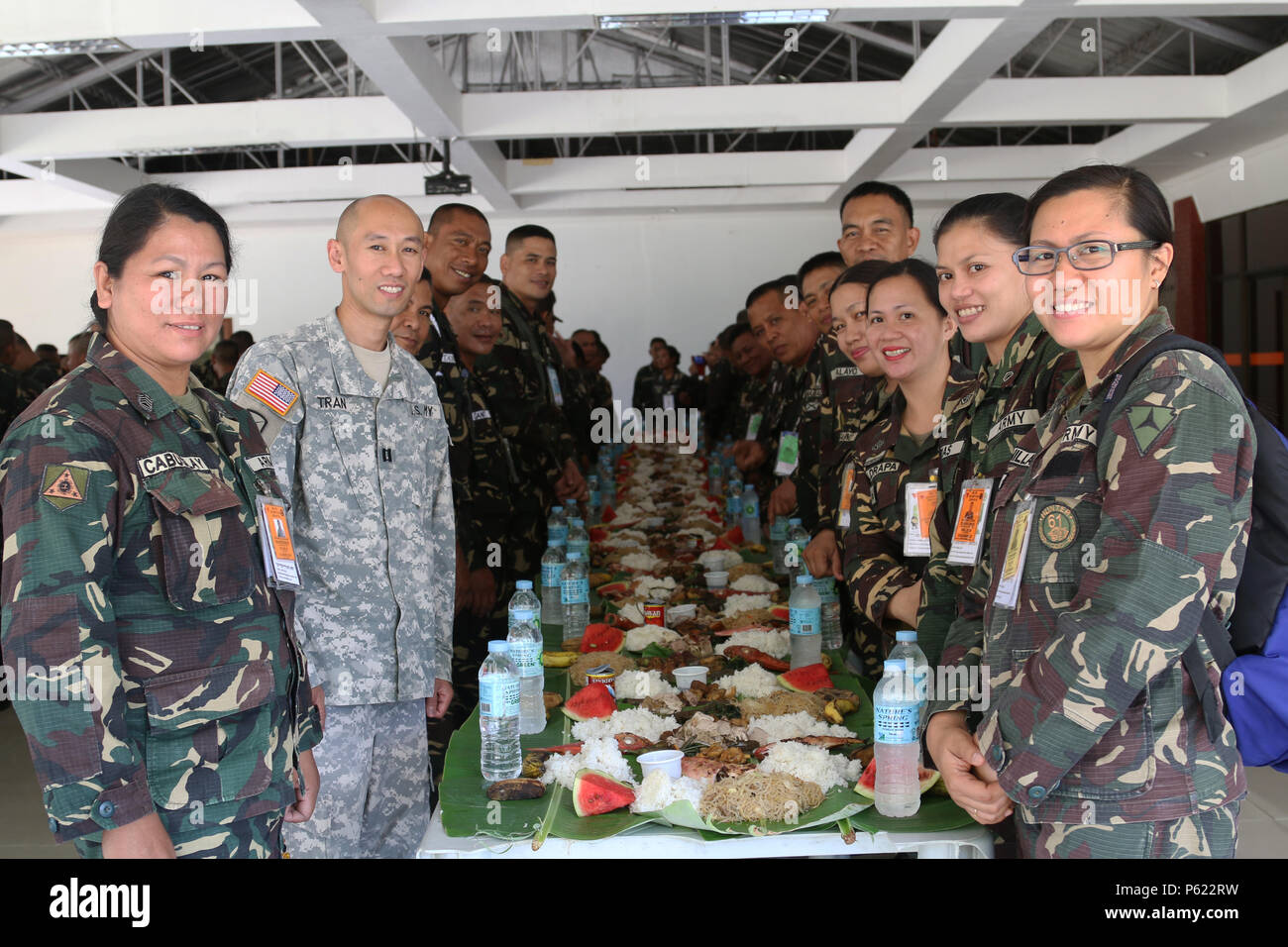 U.S. Army Reserve Cpt. Kevin K. Tran, 303rd Maneuver Enhancement Brigade, operations officer in charge in support of Balikatan 2016 CJCMOTF, and service members of the Armed Forces of the Philippines (AFP) pose for a photo before a “Boodle Fight” following the viewing at Camp Peralta, Capiz, Philippines, of a video memoir of the historical Bataan Death March of 1942, April 09, 2016. The viewing followed a flag raising ceremony. The ceremony was one of many that have brought together the AFP and U.S. military during the Balikatan 2016, “shoulder to shoulder”, exercise. Balikatan is an annual bi Stock Photo