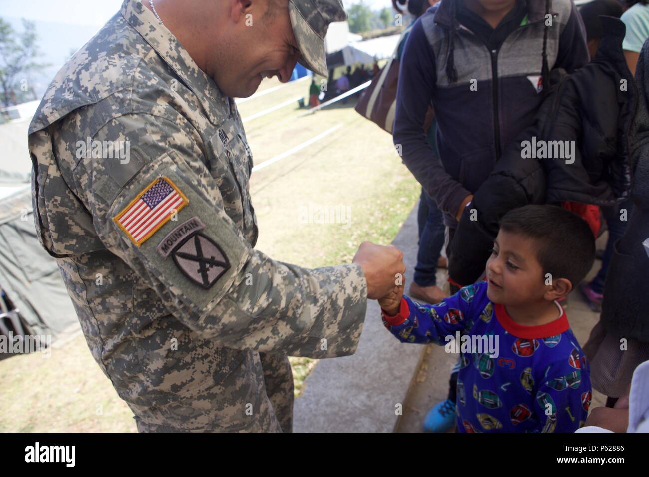 U.S. Army Sgt. 1st Class Luis Pena hands out candy to Guatemalan children outside of the Beyond The Horizon Medical Treatment area at San Marcos, Guatemala, April 14, 2016. Task Force Red Wolf and Army South conducts Humanitarian Civil Assistance Training to include tactical level construction projects and Medical Readiness Training Exercises providing medical access and building schools in Guatemala with the Guatemalan Government and non-government agencies from 05MAR16 to 18JUN16 in order to improve the mission readiness of US forces and to provide a lasting benefit to the people of Guatemal Stock Photo
