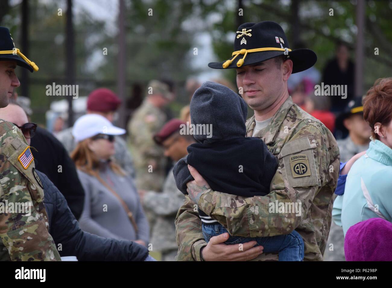 A Soldier assigned to 1st Squadron, 17th Cavalry Regiment, 82nd Combat Aviation Brigade, 82nd Airborne Division spends time with his family at Pike Field while awaiting the final OH-58D Kiowa Warrior flight over Fort Bragg and Fayetteville, N.C., April 15, 2016. Thirty-two of the helicopters, which are being retired from Army service, flew over the base and Fayetteville to thank the communites for their support over the past 25 years. (U.S. Army photo by Staff Sgt. Mary S. Katzenberger/Released) Stock Photo