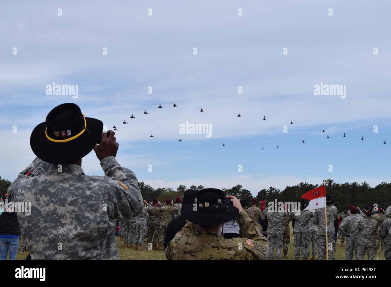 Soldiers assigned to 1st Squadron, 17th Cavalry Regiment, 82nd Combat Aviation Brigade, 82nd Airborne Division, and their family members watch the final OH-58D Kiowa Warrior flight over Fort Bragg and Fayetteville, N.C., April 15, 2016. Thirty-two of the helicopters, which are being retired from Army service, flew over the base and Fayetteville to thank the communites for their support over the past 25 years. (U.S. Army photo by Staff Sgt. Mary S. Katzenberger/Released) Stock Photo