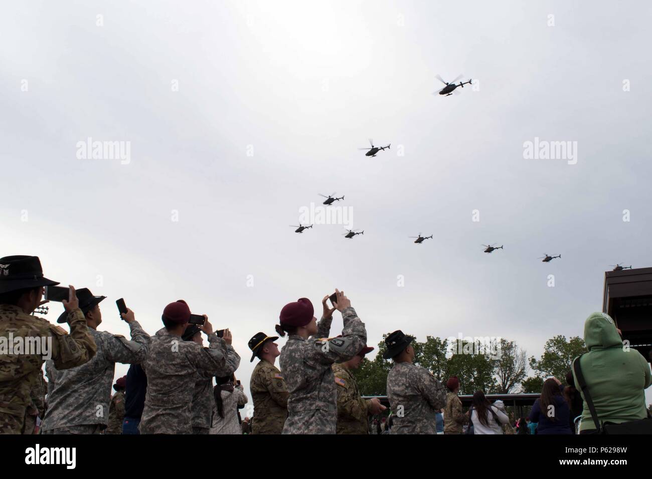 Soldiers assigned to 1st Squadron, 17th Cavalry Regiment, 82nd Combat Aviation Brigade, 82nd Airborne Division, and their family members watch the final OH-58D Kiowa Warrior flight over Fort Bragg and Fayetteville, N.C., April 15, 2016. Thirty-two of the helicopters, which are being retired from Army service, flew over the base and Fayetteville to thank the communites for their support over the past 25 years. (U.S. Army photo by Staff Sgt. Mary S. Katzenberger/Released) Stock Photo