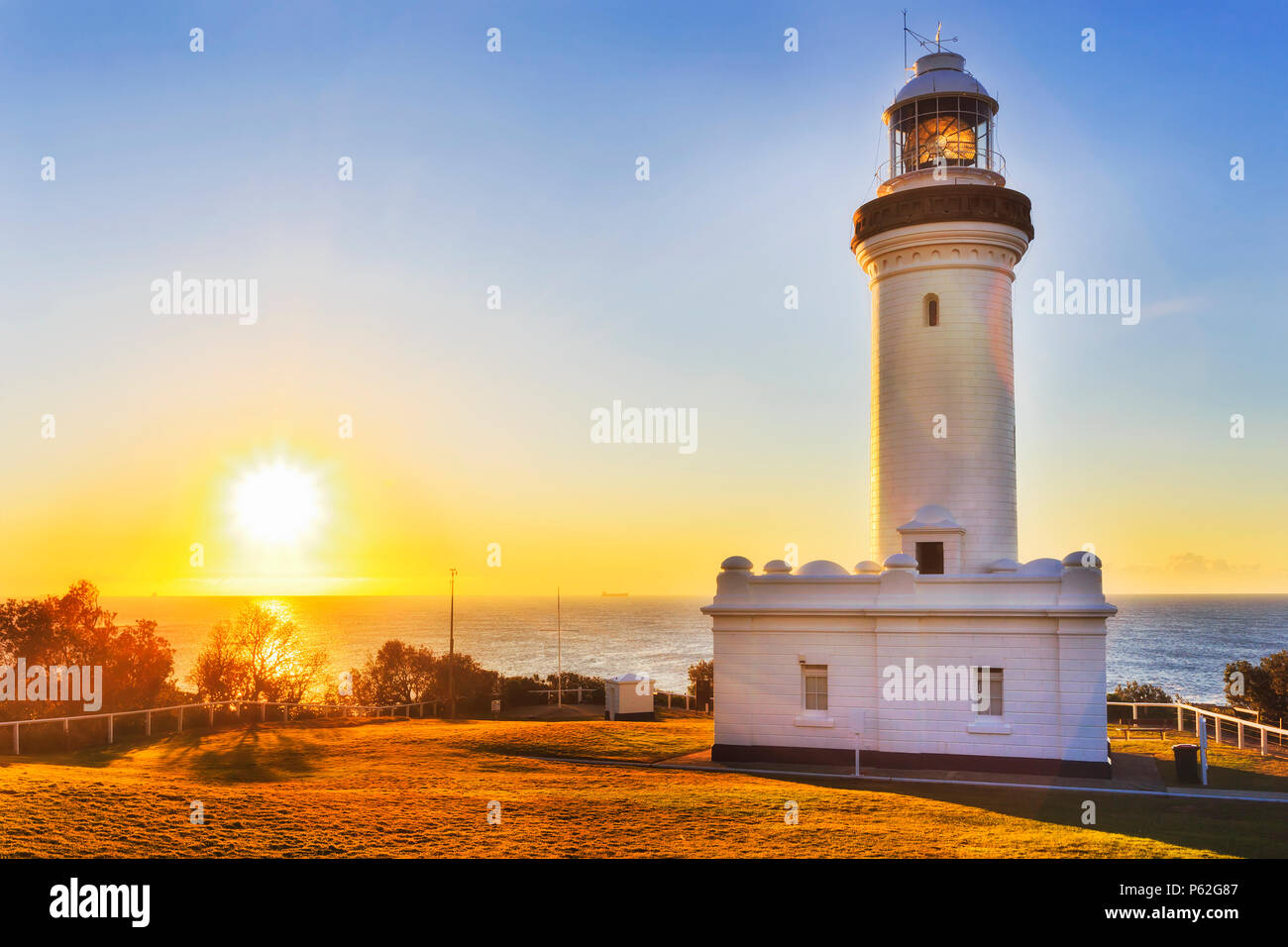 Warm filling sun light rising above open sea horizon off Pacific ocean behind Norah head lighthouse on Australian's central coast. Stock Photo